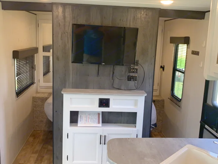 RV rental's functional living space: TV, media console, and a cozy sleeping area. Enjoy modern camping comfort.. Keystone Hideout 2022