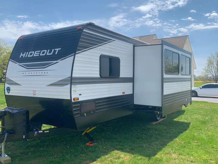 Modern Keystone Hideout travel trailer, great for an rv rental, is parked outdoors with its side expanded.. Keystone Hideout 2022
