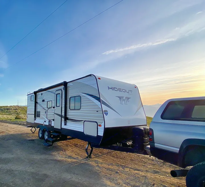 RV rental trailer hooked to a truck at sunset, ready for adventure camping in nature.. Keystone RV Hideout 2018