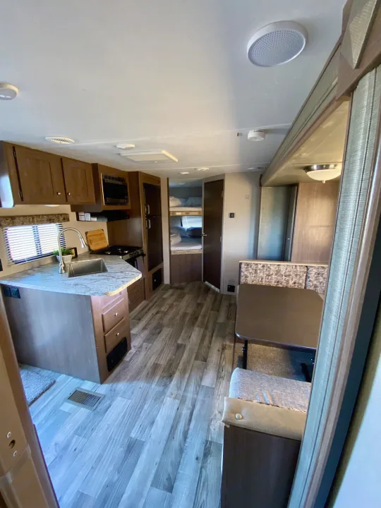 Interior view of an RV rental with full kitchen, dining booth, and bunk beds in the rear section.. Keystone RV Hideout 2018