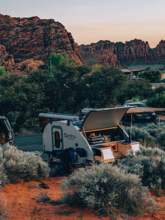 An Opindrop teardrop rv rental is set up in a red rock desert campsite with an open kitchen, perfect for nature travel.. Pindrop Travel Trailer Fina Roma 2022