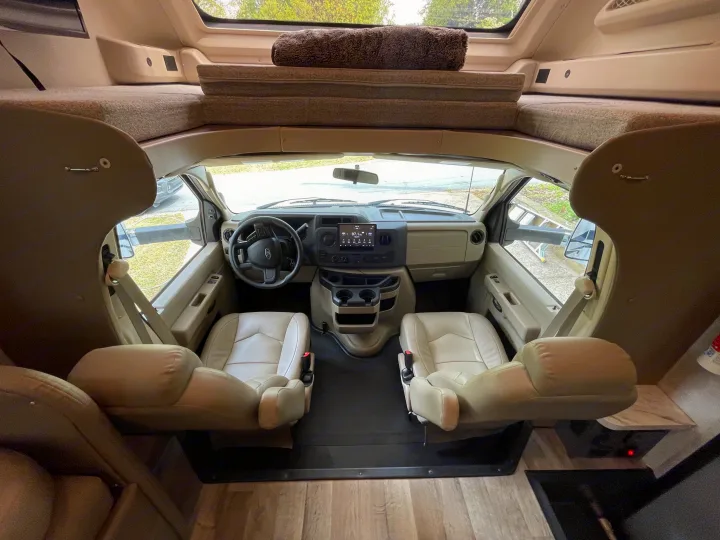 Inside this RV rental: view of the clean cockpit, steering wheel, seats, and comfy overhead bunk bed.. Jayco Greyhawk 2023