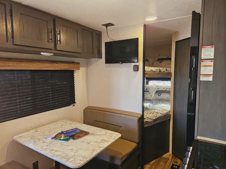 Cozy RV rental interior with dinette, bunk beds, and overhead storage, perfect for family travel and camping.. Dutchmen TT 2024
