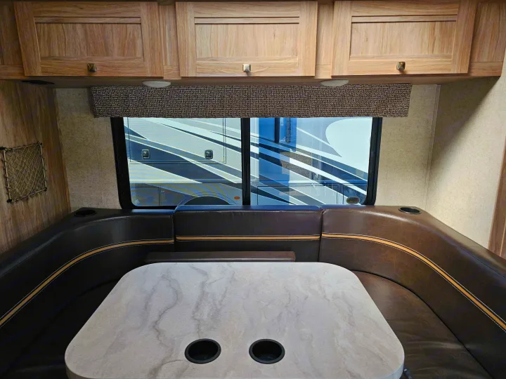 Inside an RV rental: a comfortable dinette featuring U-shaped booth seating, a table, and overhead cabinets.. Forester 2421MS 2019