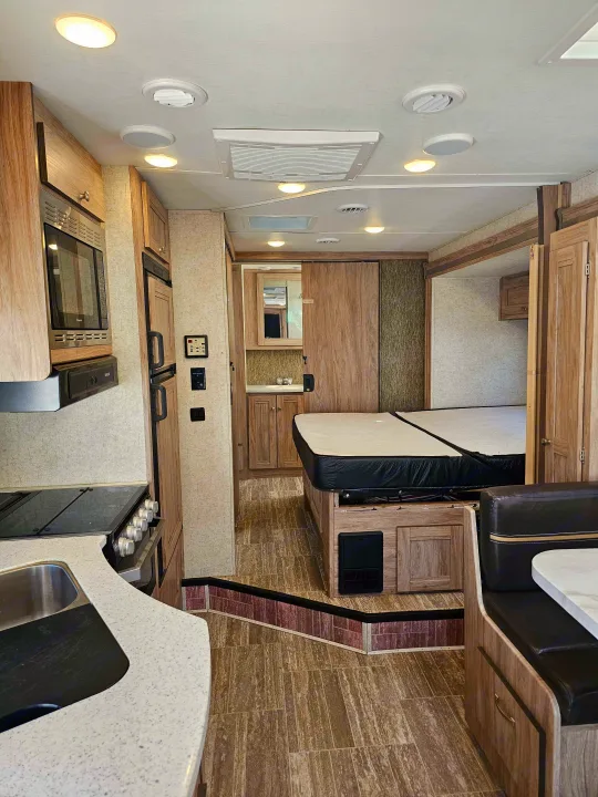 Inside a modern RV rental: complete kitchen, comfortable bedroom, and dining booth. Perfect for road trips.. Forester 2421MS 2019