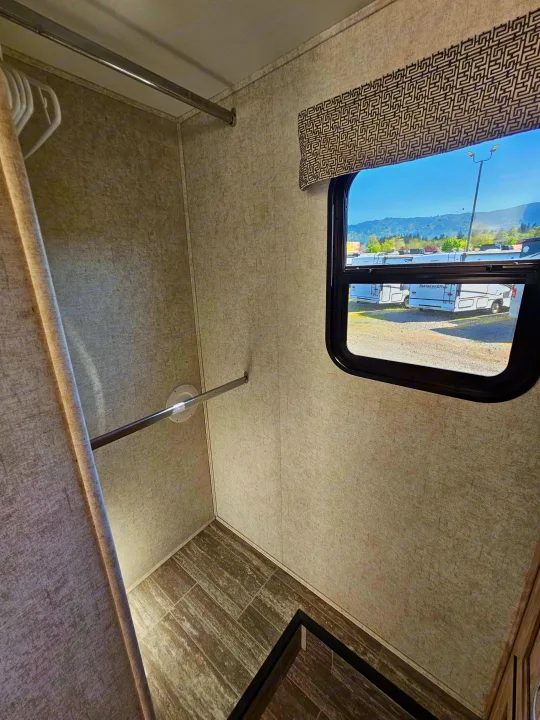 Spacious RV rental interior features a closet with hanging rods, tile flooring, and a window view of a sunny RV lot.. Forester 2421MS 2019