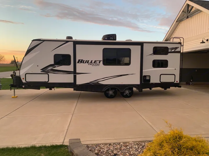 Modern RV rental: a white travel trailer parked on a driveway at sunset, ready for adventure.. Keystone RV Bullet Ultra Lite 2021