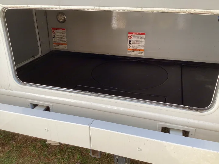 View into an RV rental's accessible cargo storage compartment, highlighting safety warnings and 500 lbs max capacity.. Thor Majestic 2019