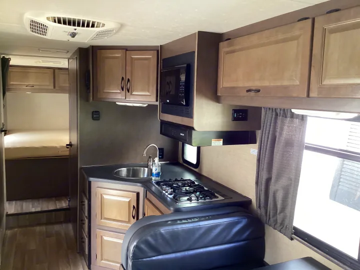 RV rental interior: well-equipped kitchen with sink, stove, microwave, storage, and cozy bunk beds.. Thor Majestic 2019