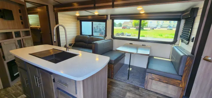 Spacious RV rental interior with a kitchen island, dinette, and sofa. Modern and functional for your travels.. Crossroads Sunset Trail 2022