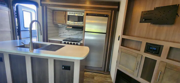 Modern RV rental interior featuring a full kitchen with sink, stove, microwave, fridge, and an entertainment area.. Crossroads Sunset Trail 2022