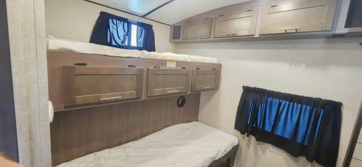 RV rental bedroom with comfortable bunk beds, smart storage, and window, ideal for camper travel.. Crossroads Sunset Trail 2022