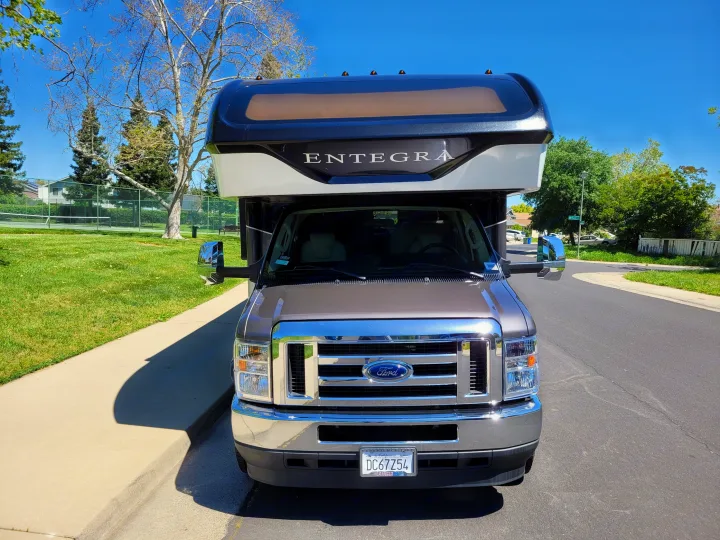 Front view of a brown and white Entegra Ford motorhome, ideal for rv rental, parked on a sunny street.. Entegra Coach Esteem 2021