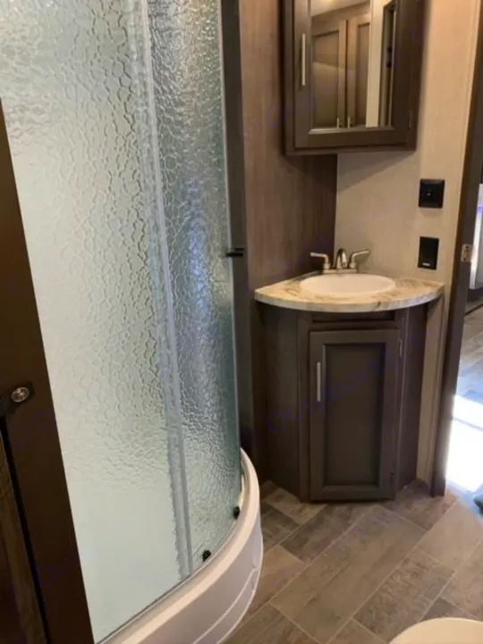 RV rental bathroom: compact corner vanity with sink, mirror, and textured glass shower enclosure.. Crossroads Sunset Trail 2021
