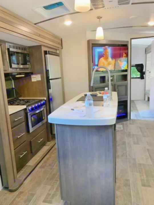 Spacious RV rental interior with kitchen island, appliances, and TV. Ideal for comfortable travel adventures.. Crossroads Sunset Trail 2021