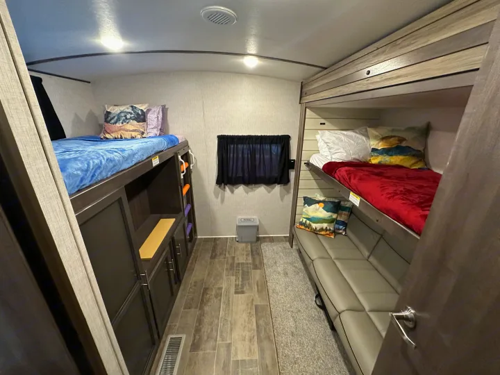 This RV rental offers comfortable bunk beds with colorful bedding, a sofa, and integrated storage.. Crossroads Sunset Trail 2021