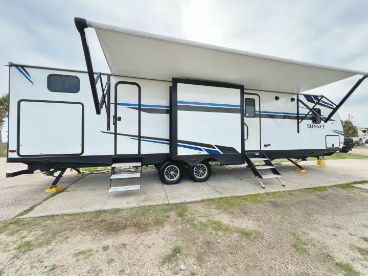 White travel trailer RV rental, ready for camping with extended awning, steps, and leveling blocks on a concrete pad.. Crossroads Sunset Trail 2021