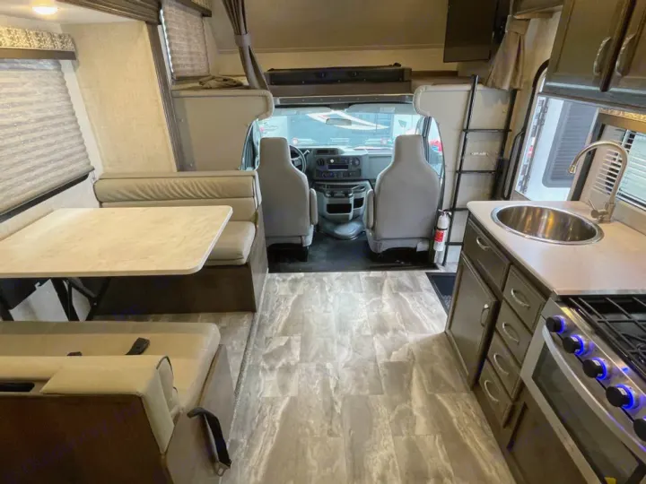 Spacious RV rental interior with light wood-look flooring, dining area, kitchen, and cab-over bunk.. Gulf Stream Conquest 2023