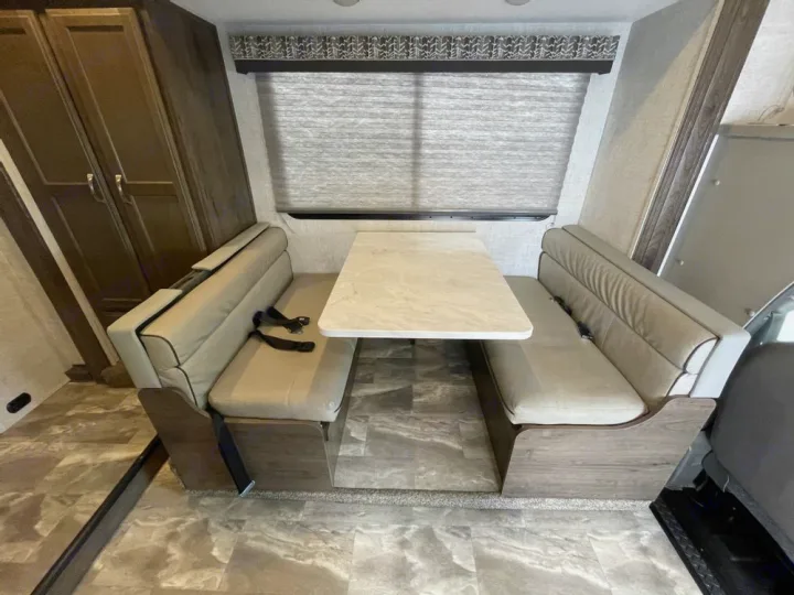 RV rental interior: A beige dinette area with a dining table and belted bench seating.. Gulf Stream Conquest 2023