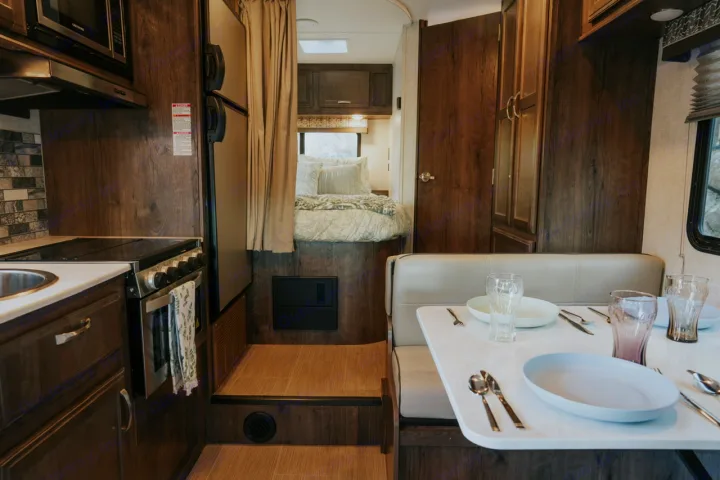Well-appointed RV rental interior with a functional kitchen, set dining area, and bedroom for comfortable travel.. Gulf Stream Conquest 2023