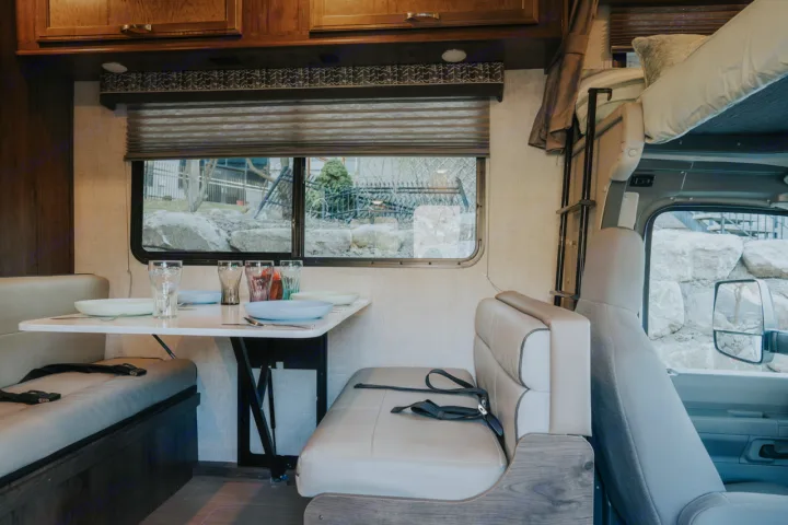 Cozy RV rental interior with dining area, bunk bed, and cab seats. Ready for your next adventure.. Gulf Stream Conquest 2023