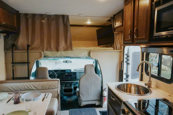 Spacious RV rental interior featuring a kitchen, dinette, and bunk over the cab. Perfect for your next mobile adventure.. Gulf Stream Conquest 2023