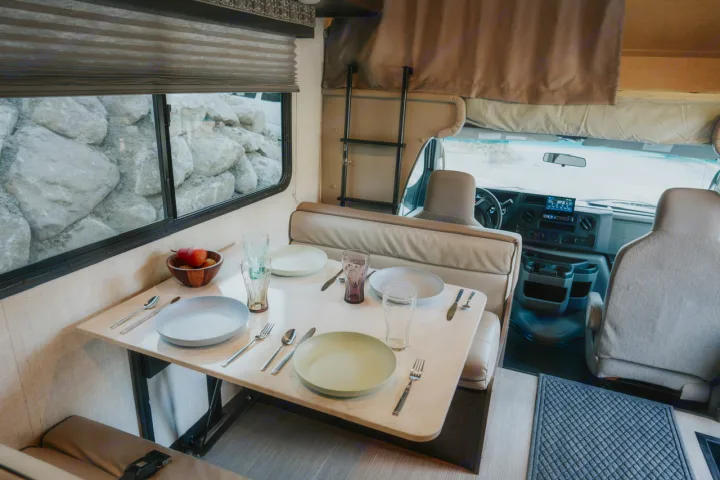 Explore this RV rental's cozy interior: A dinette set for dining, with a view of rocks outside, plus the front cockpit.. Gulf Stream Conquest 2023