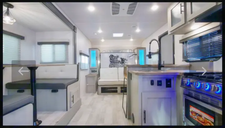 Inside a modern RV rental: a bright interior with full kitchen, dining booth, and versatile living/sleeping area.. Forest River IBEXMBS 2023