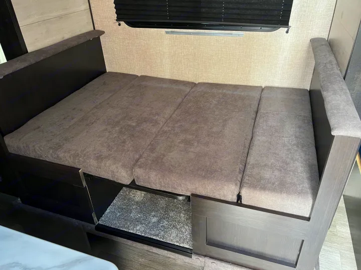 This RV rental shows a dinette converted to a bed with pull-out storage below, maximizing space for travelers.. Jayco Jay Flight SLX 2023