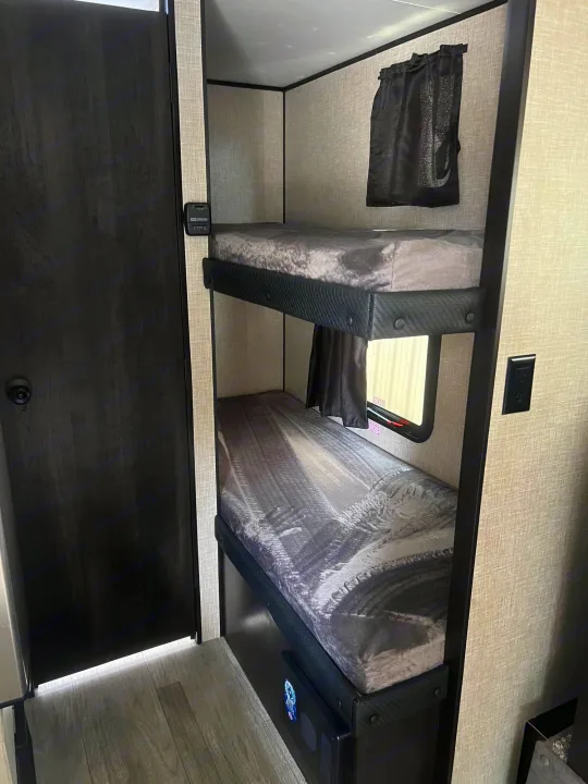 RV rental: Cozy bunk beds with dark curtains and a control panel. Perfect sleeping area inside this RV.. Jayco Jay Flight SLX 2023