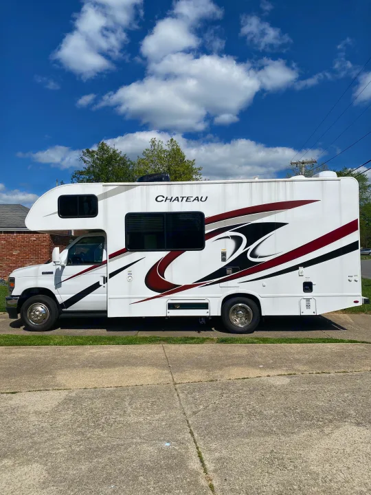 White Chateau RV rental, a stylish motorhome with maroon and black graphics, parked on a sunny day.. Ford F350 22E MC 2023