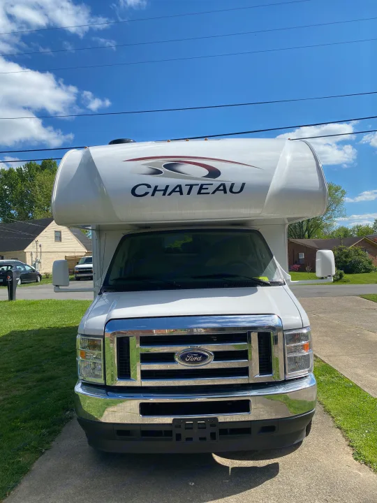 White Ford Chateau Class C RV rental parked on a driveway under a clear blue sky, ready for your next adventure.. Ford F350 22E MC 2023