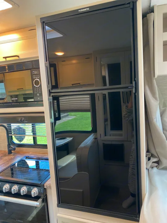 View inside an RV rental showing kitchen appliances: Dometic fridge, Greystone microwave, Furrion oven, & stovetop.. Ford F350 22E MC 2023