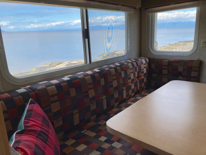 Serene RV rental interior: cozy checkered seating & table with panoramic ocean views and distant mountains.. Chevrolet Other 2010