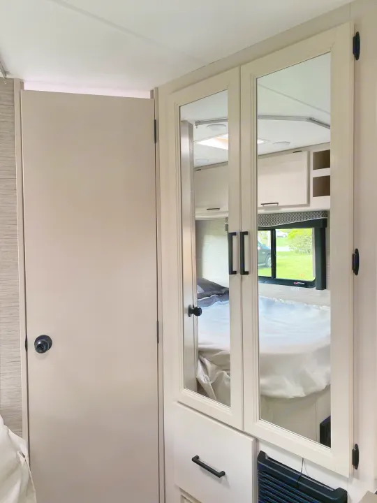 Step inside this cozy RV rental! Mirrored wardrobe doors reflect the compact bedroom area and bright interior. Perfect for your next adventure.. Ford F350 22E MC 2023