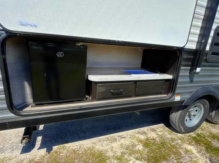 RV rental outdoor kitchen setup features a mini-fridge, sink, and storage drawers, ideal for camping.. Jayco Jay Flight SLX 2022