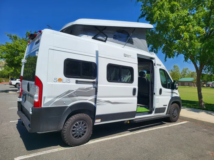 White Solis pop-top RV rental parked by a grassy park, ready for adventure.. Winnebago Solis 2024