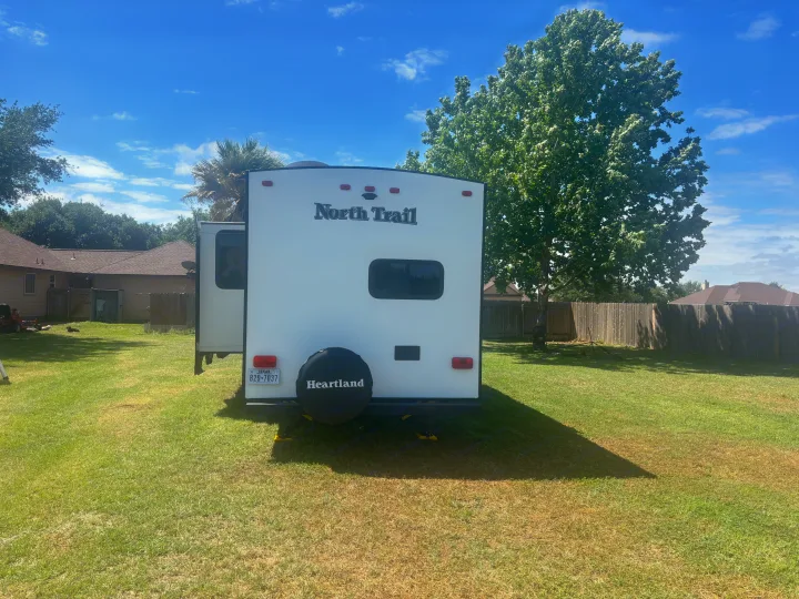 White North Trail Heartland RV rental parked in a sunny backyard with an open slide-out. Texas plate visible.. Heartland RVs North Trail 2018
