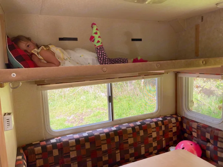 Child rests comfortably in an RV rental bunk bed with colorful socks, enjoying a family camping trip.. Chevrolet Other 2010
