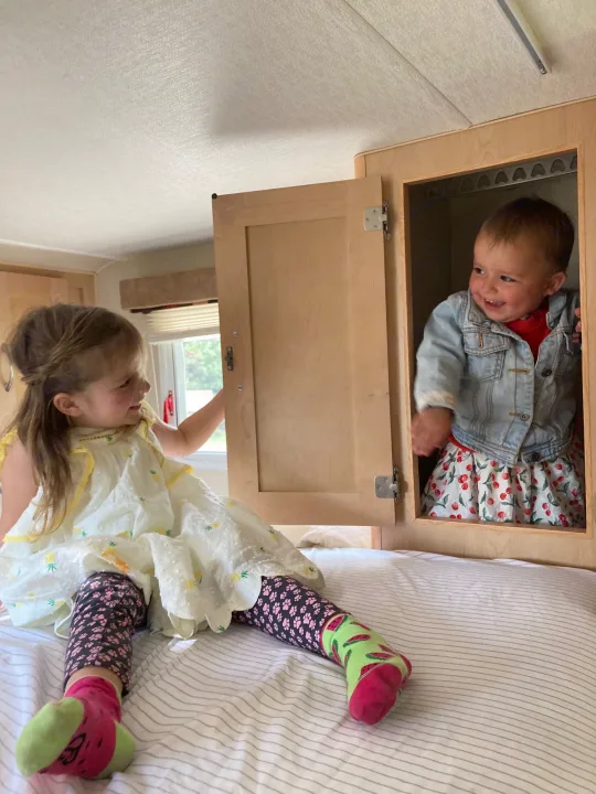 Two happy children playing in an RV rental. One peeks from a cabinet, the other smiles on the bed.. Chevrolet Other 2010