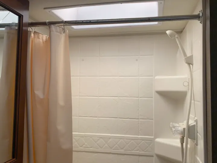 RV rental shower interior: light curtain, shower rod, white tiled walls, and a shower head. Features an overhead skylight.. Thor Motor Coach Chateau 2017