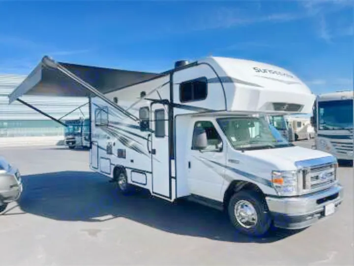 White Class C motorhome with an extended black awning. This RV rental is ready for adventure in a sunny lot.. Forest River Sunseeker LE 2023