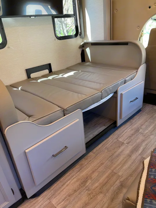 RV rental interior showing a light grey sofa converting to a bed, with convenient under-seat storage drawers.. Thor Coleman 2024