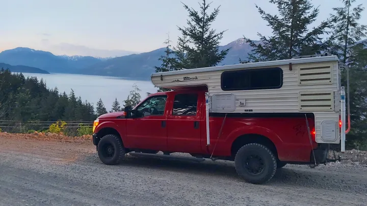 Red Hallmark truck camper, your scenic RV rental, overlooking a stunning mountain lake.. Ford F350 2015