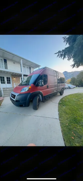 Red adventure camper van for RV rental, parked on a driveway with a white house & snowy mountains visible.. Dodge RAM Dodge RAM Promaster 2500 2021