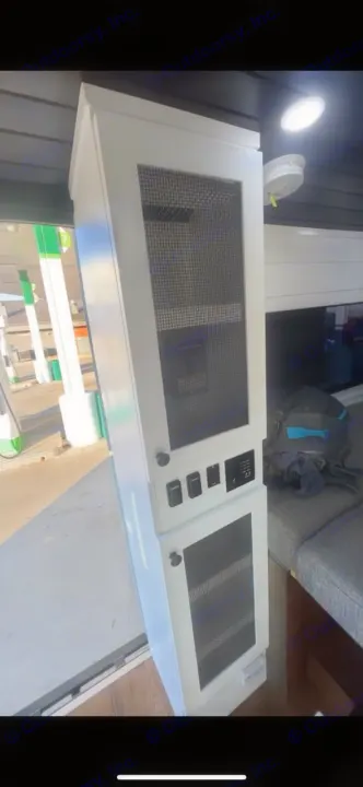 RV rental interior: White cabinet with power control panel, switches, and vented storage doors. A gas station is visible outside.. Dodge RAM Dodge RAM Promaster 2500 2021