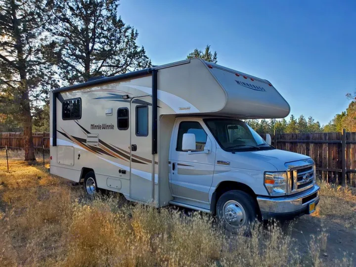Class C RV rental: A Winnebago Minnie Winnie motorhome parked in dry grass under clear skies, ready for adventure.. Winnebago Minnie Winnie 2017