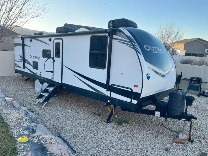 Spacious Outback Ultra-Lite travel trailer, perfect for an RV rental. Parked on gravel with scenic mountain views.. Keystone RV Outback Ultra-Lite 2020