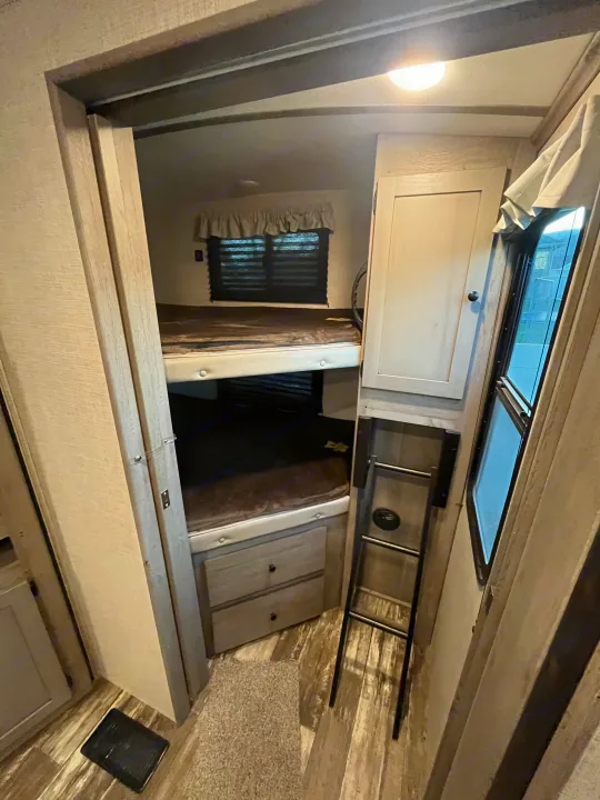 Explore this **rv rental**'s cozy bunk room with stacked beds, integrated drawers, and a window.. Keystone RV Outback Ultra-Lite 2020