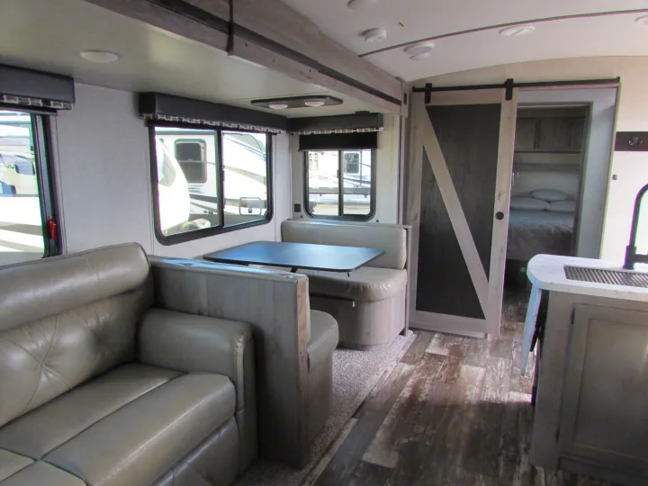 Spacious RV rental interior: comfy sofa, dinette area, and modern barn door leading to the bedroom. Perfect for travel.. Keystone RV Outback Ultra-Lite 2020